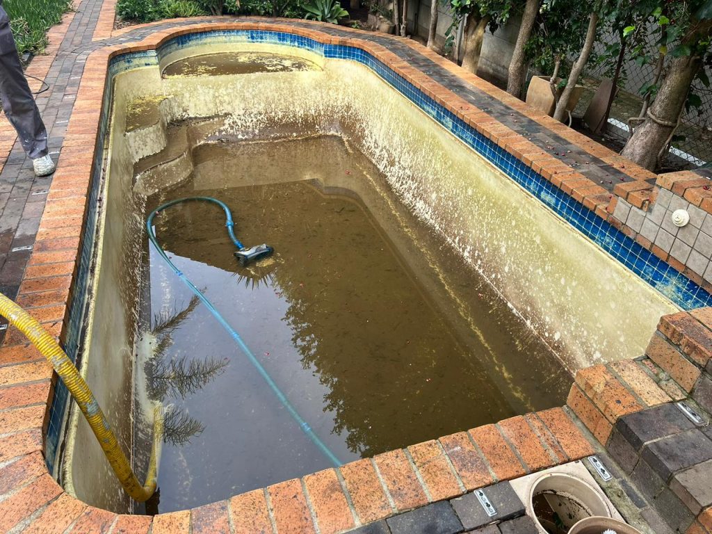 Drained pool showing the damaged surface before repairs