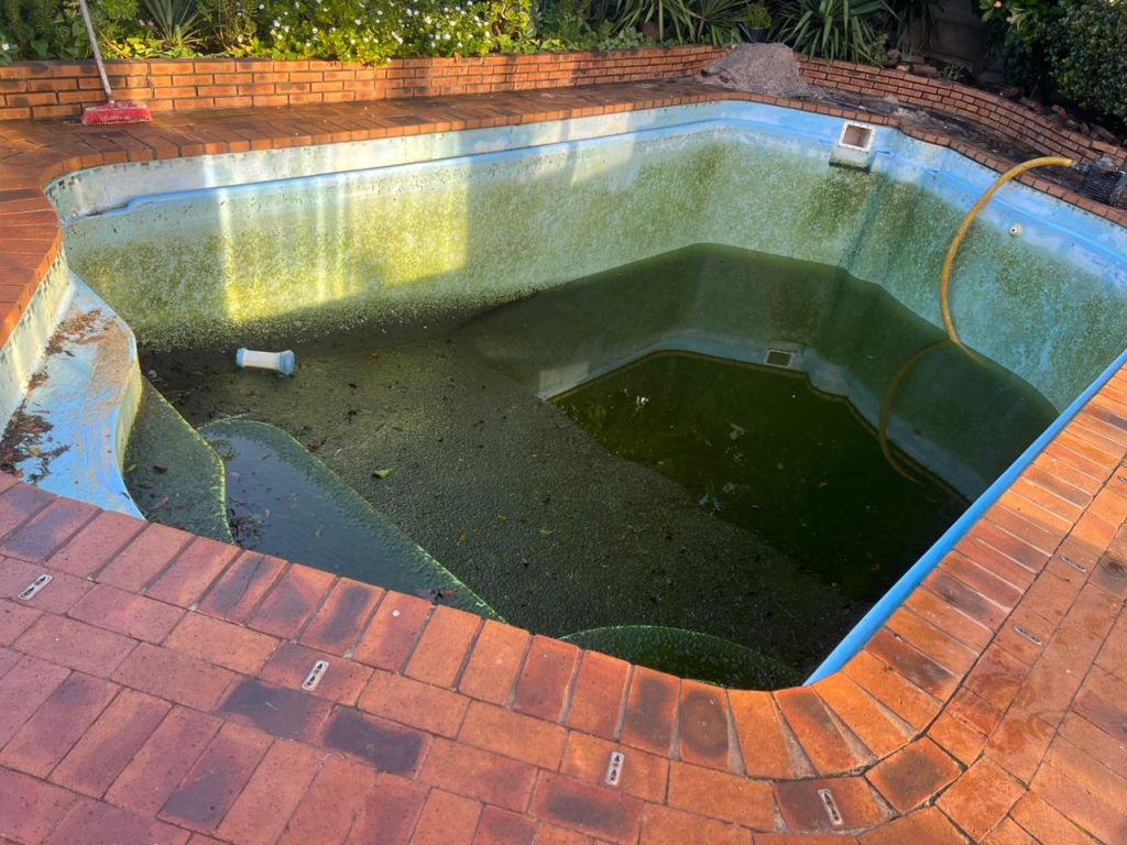 Drained pool showing the damaged surface before repairs