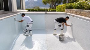 Cape Town pool workers comparing fibreglass lining and marbelite resurfacing inside a residential swimming pool
