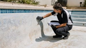 Pool specialist checking rough marbelite, staining and surface cracks during a resurfacing inspection