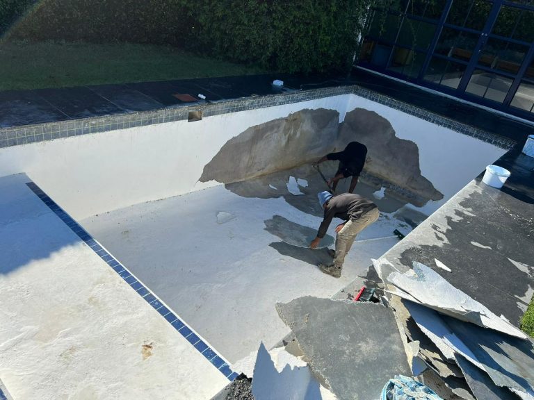 Old pool lining stripped out of an empty swimming pool ahead of a fibreglass relining