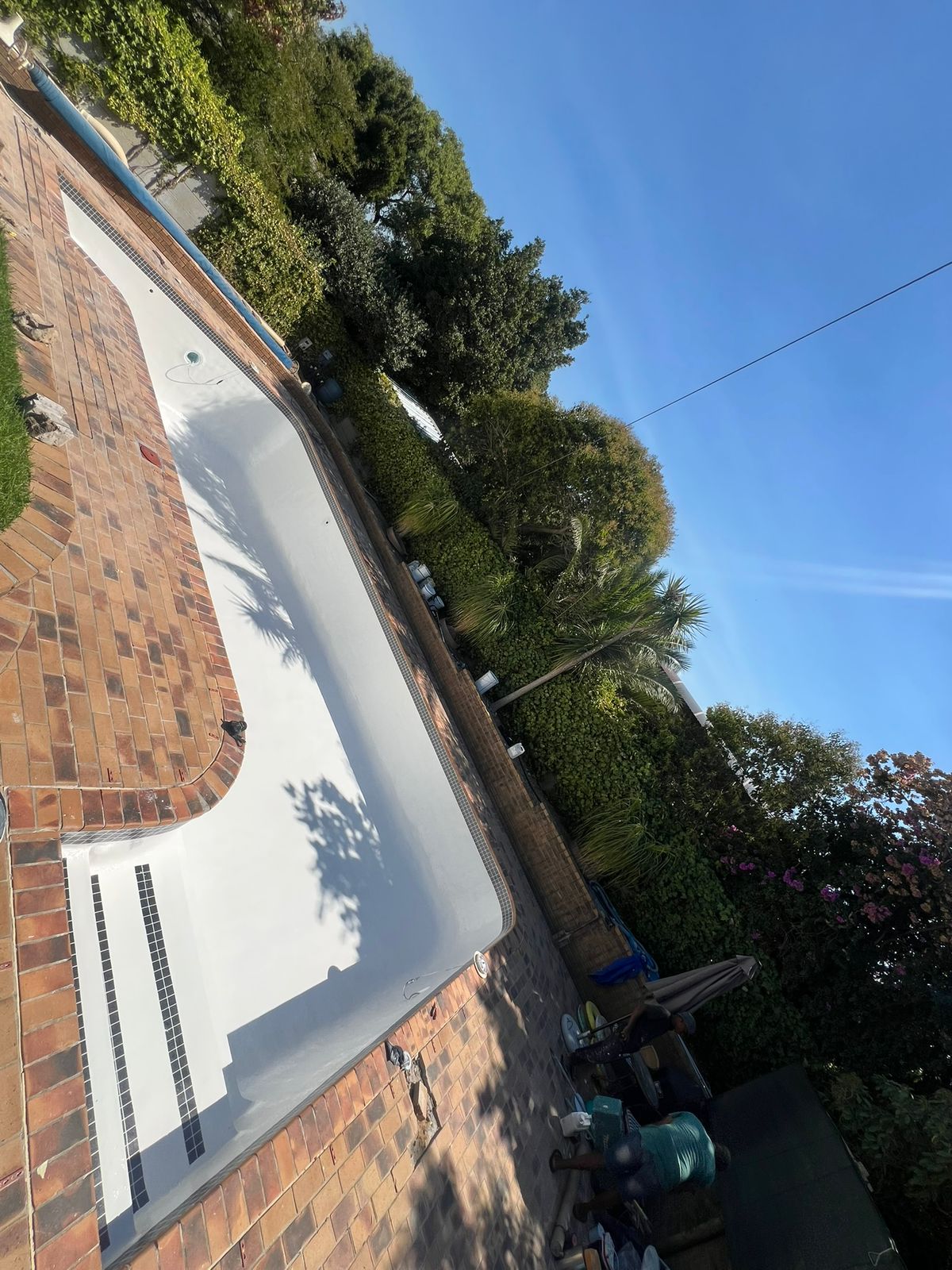 Swimming pool with a newly applied white finish and built-in steps after renovation