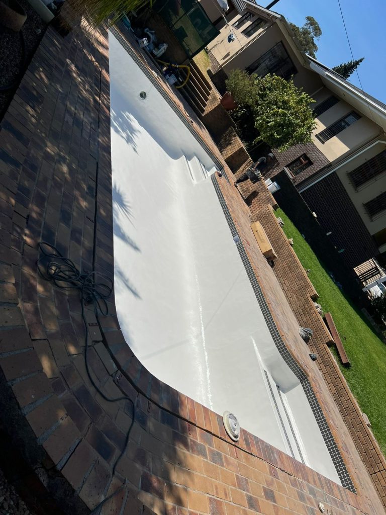 Freshly resurfaced swimming pool interior with a brick paving surround