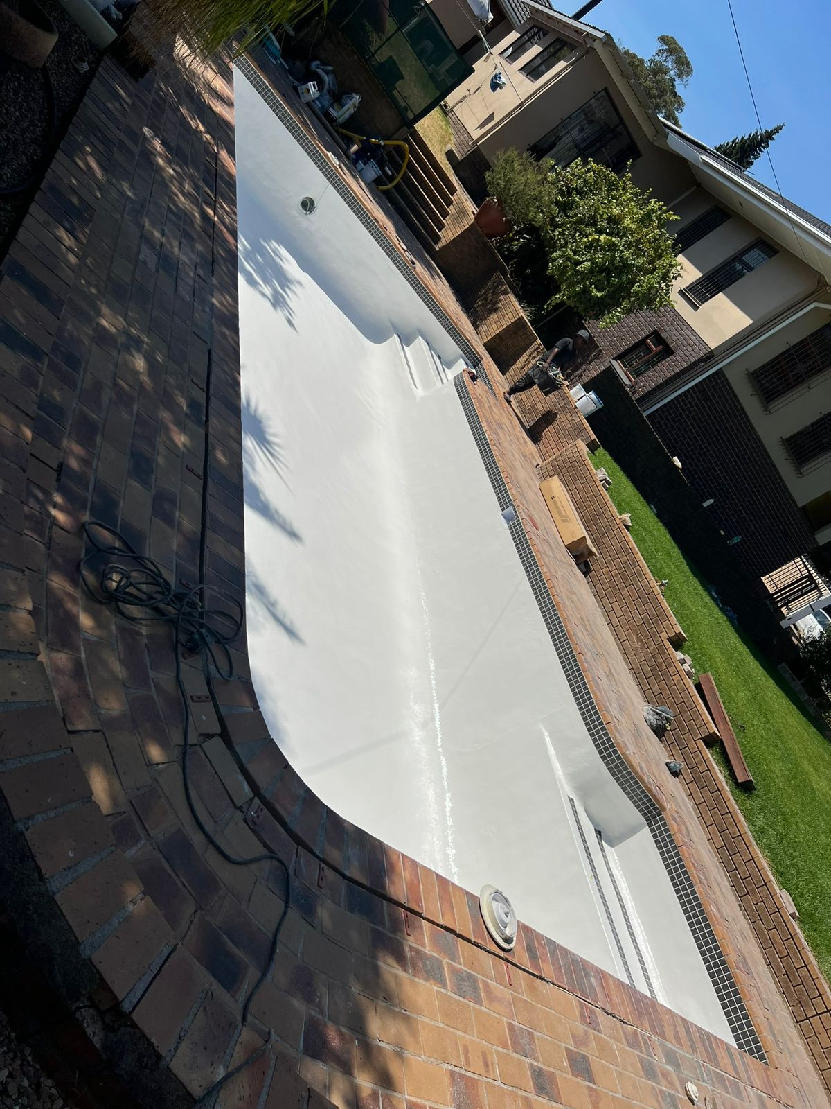 Freshly resurfaced swimming pool interior with a brick paving surround