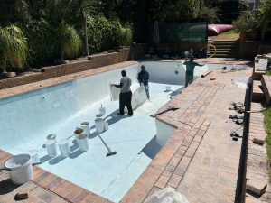 Aquatic Pools team resurfacing a drained swimming pool in a Cape Town garden